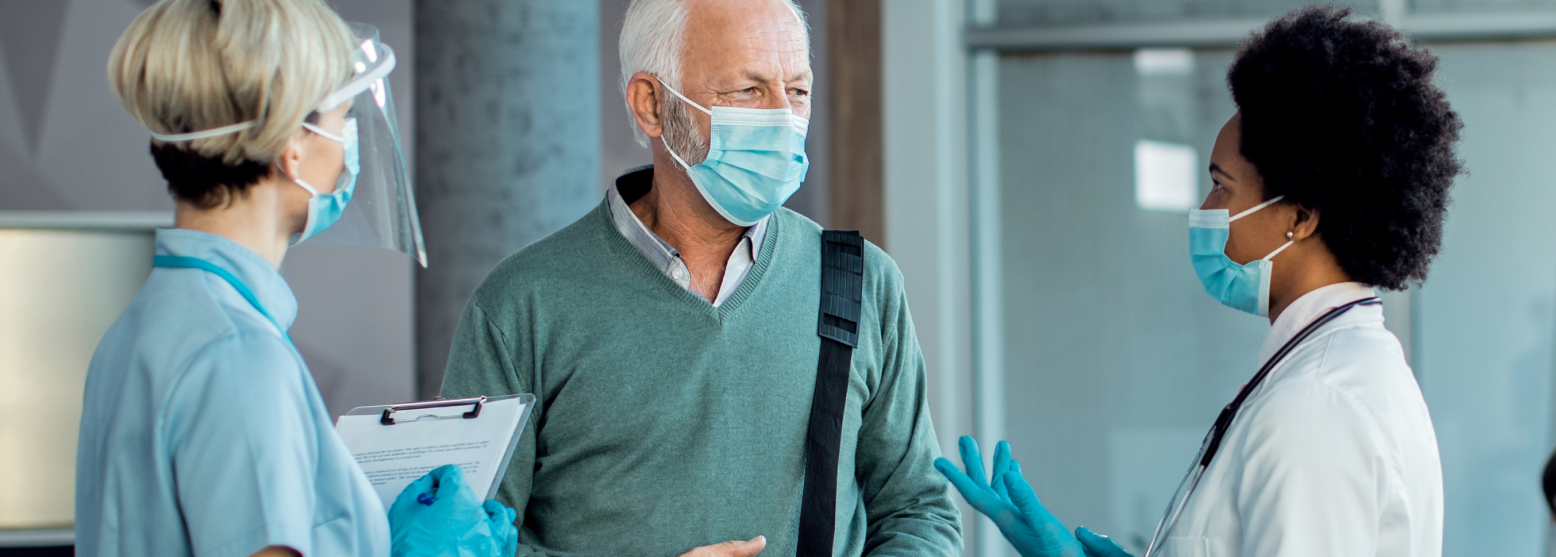 senior-man-with-protective-face-mask-talking-doctors-hospital-hallway 1